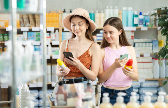 Mother and daughter carefully scan the barcode of the repellent on their mobile and read detailed instructions for use and how to spray correctly