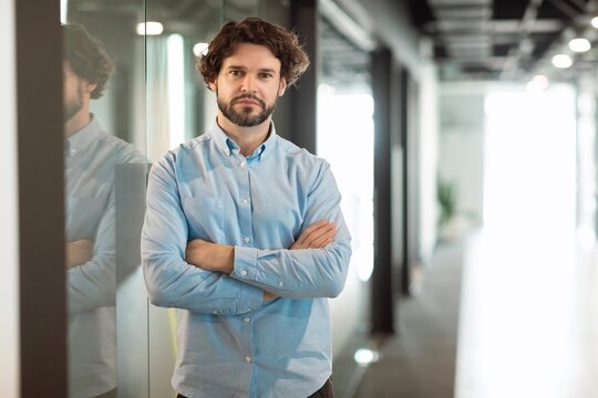 Focused Man In Formal Attire, Crossed Arms, Standing In Office Environment, Displaying Confidence And Professionalism, Modern Setting, Business Concept.