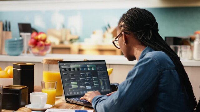 Woman focuses on programming and software development while laptop screen displays code, scripts and binary data for system maintenance during remote work.