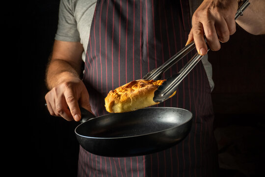 In a warmly lit kitchen, a skilled cook expertly flips a fluffy omelette using tongs. The scene captures the joy of cooking and the enticing aroma filling the space