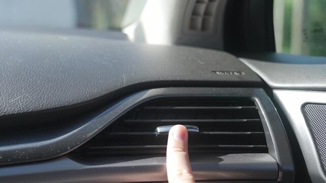 Person adjusts dashboard air vent with finger inside car. Changing airflow direction as part of vehicle ventilation and climate control