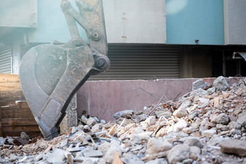 Excavator bucket resting on rubble at an urban demolition site © Burak