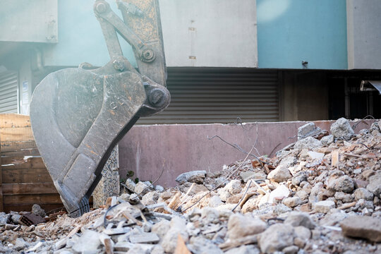 Excavator bucket resting on rubble at an urban demolition site