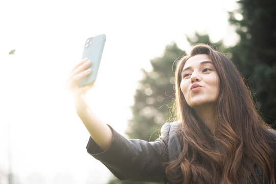 Young woman pouting her lips for a playful selfie outdoors