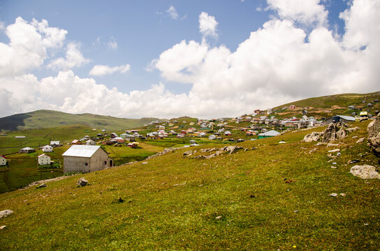 Highland village on a green plateau under cumulus clouds in summer