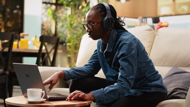 Close-up woman makes a hand gesture for rhythm on coffee table at home, listening to groovy music while working on tasks. Adult digital nomad multitasks with a music player and works from home.