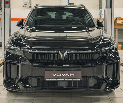 Black Voyah Free Sport Edition 4WD EREV hybrid SUV car with a 1.5L turbo engine and 490 hp electric motors parked on a lift platform inside a dealership showroom repair shop. Premium Chinese vehicle.