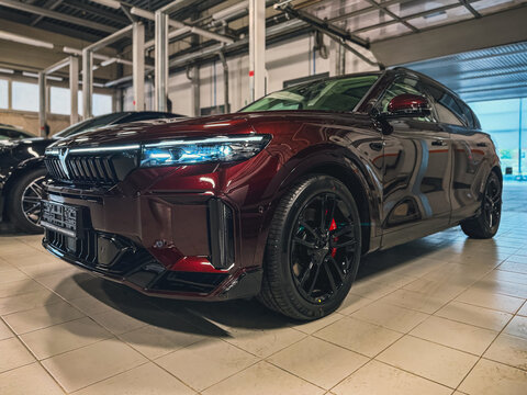 Burgundy Voyah Free Sport Edition 4WD EREV hybrid SUV car with a 1.5L turbo engine and 490 hp electric motors parked inside a modern automotive dealership showroom. Premium Chinese EV automobile.