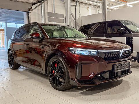 Burgundy Voyah Free Sport Edition 4WD EREV hybrid SUV car with a 1.5L turbo engine and 490 hp electric motors parked inside a modern automotive dealership showroom. Premium Chinese EV automobile.