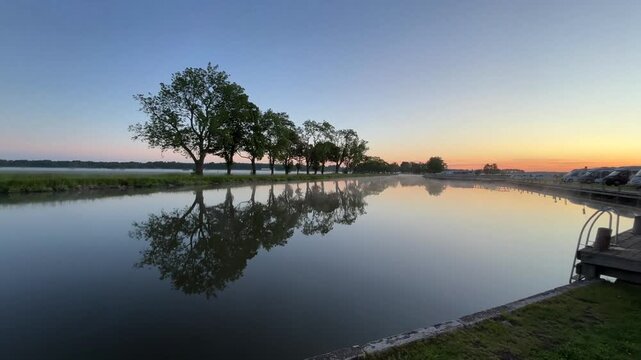 Trees and sunset reflected in calm water, morning fog, campground, G&ouml;ta Canal, Jonsboda Camping, T&ouml;reboda, V&auml;stra G&ouml;talands l&auml;n, Sweden