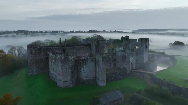 Raglan Castle in the fog at dawn from a drone, Monmouthshire, Wales, England, United Kingdom