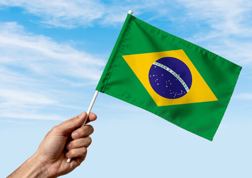 Brazil national flag held by hand on white background, isolated patriotic symbol representing national identity, pride and culture.