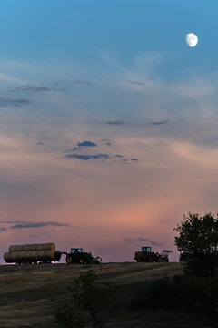 Vertical twilight farm scene with tractors and moon