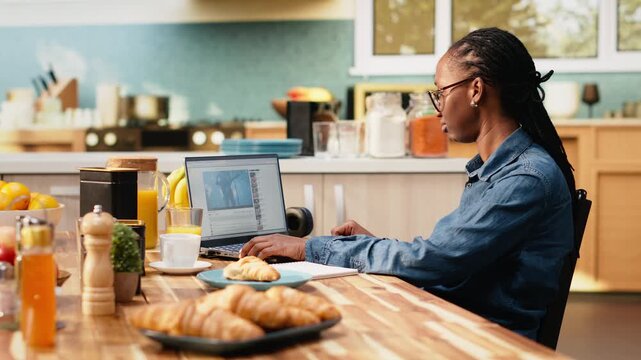 African american woman having fun with live concert broadcast on laptop, using streaming platform and social media feed for entertainment and relaxation.