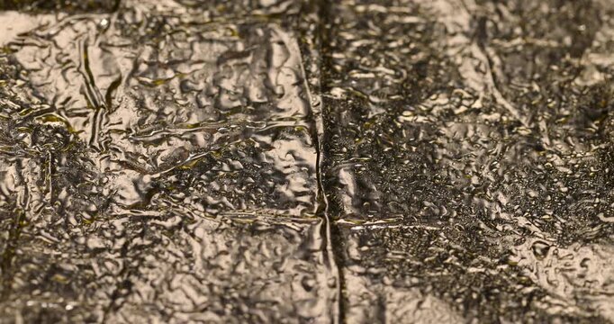 Wet crumpled foil texture with shiny reflections, aluminum wrap material with fine clear moisture water drops on wrinkled pattern