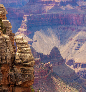 Layered sandstone cliffs and rugged rock formations overlooking expansive canyon depths in dramatic light at Grand Canyon National Park, Arizona landscape