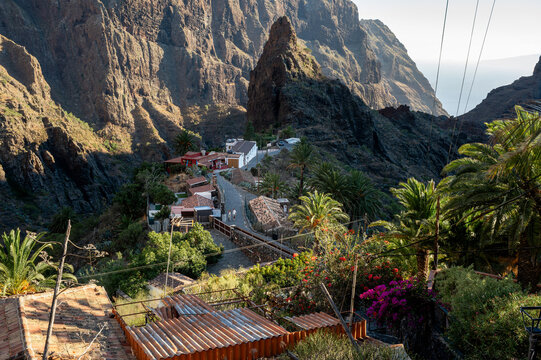 Power lines cross above the corrugated roofs and terraces of Masca as the road loops through the village. Everyday life in a remote mountain settlement rather than the postcard version.