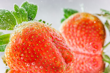 Close-up of fresh, ripe strawberries covered in tiny carbonated bubbles, set against a plain light background. © tai