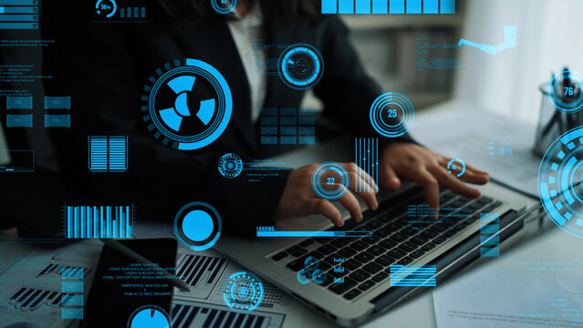A business professional focuses on a laptop while surrounded by abstract digital interface and data visualization elements, showcasing modern technology in an office environment. Xenic