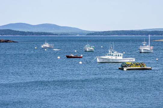 BAR HARBOR, MAINE &mdash; JUNE 20, 2018: Fishing boats and a work float loaded with lobster traps occupy the harbor off Bar Harbor.