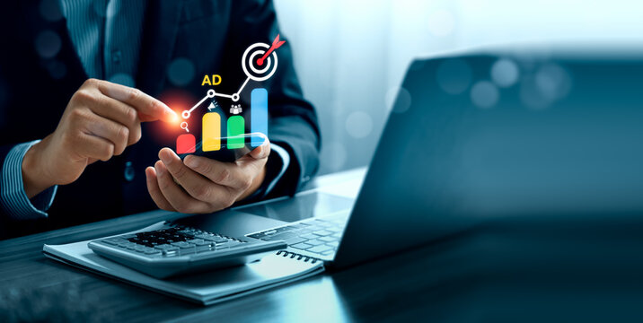 Digital marketing performance concept with business professional using smartphone beside laptop showing advertising growth chart, target campaign analytics and online ad strategy