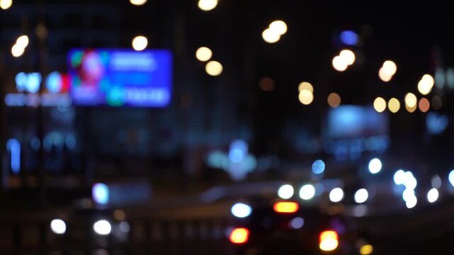Intentionally defocused night traffic with glowing headlights and colorful city bokeh, creating an abstract urban background for transportation, commuting, mobility and modern city life