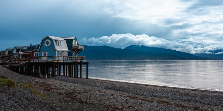 Homer Spit bay harbor seascape, cloudscape over Kenai Mountains, and landmark beach architecture in Alaska, United States