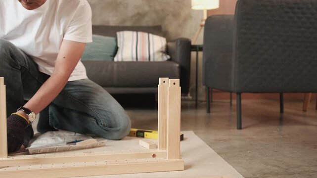 Close-up, Asian man nailing joint parts with rubber mallet, self-assembling flat-pack furniture with DIY tools, home improvement, craft installation, hobby wooden workshop, handyman active lifestyle.