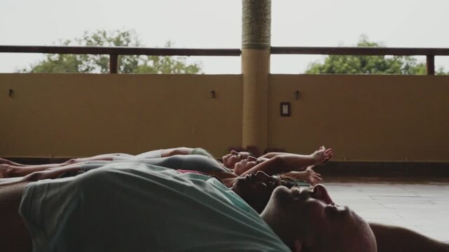 Group of people meditating in savasana pose during a yoga class at a wellness retreat center