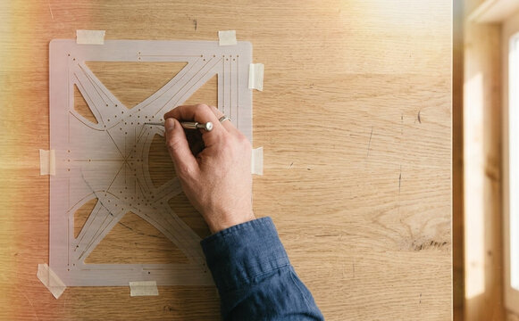 Architect using stencil and drafting tool on wooden table to create precise design for creative project