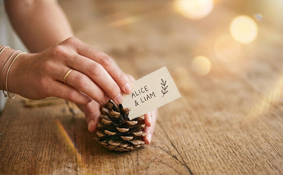 Woman making rustic pinecone place card holder for rustic wedding reception decor and autumn dining table setting