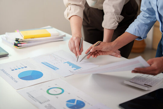 Business partners pointing at financial expense reports on desk for corporate accounting