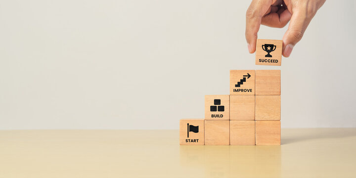 Step by step wooden blocks with START, BUILD, IMPROVE, and SUCCEED icon. Business growth, progress, achievement and long term success concept.