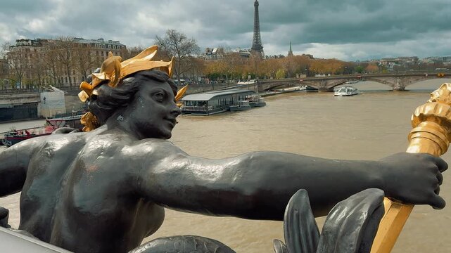 Sculptures on Pont Alexandre III overlook the Seine River and distant Eiffel Tower with cruise boats sailing under cloudy Parisian skies during a scenic daytime visit to France.

