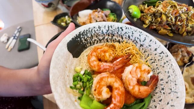 Holding Bowls of Burmese Shan Noodles and Tea Leaf Salad