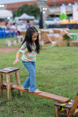 Obraz na płótnie Canvas preschool child girl walking on wooden balance beam in park