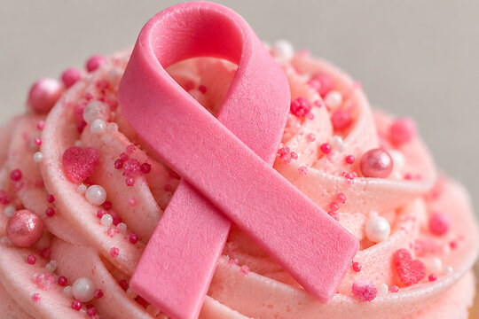Macro sur un cupcake gla&ccedil;age rose surmont&eacute; d'un ruban de sensibilisation Octobre Rose