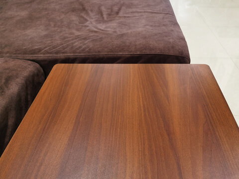 Close-up of modern wooden table top with brown sofa background.