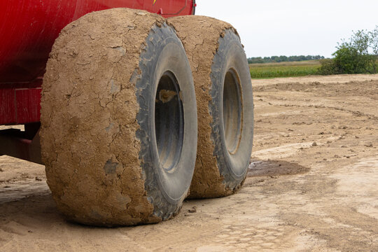 Agricultural tractor tires caked with mud on farm field after harvest