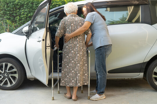 Caregiver help Asian elderly woman disability patient get into car.