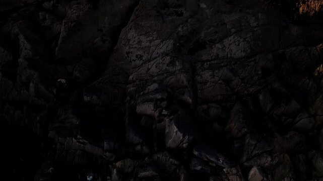 Aerial footage of a rocky coastline greenish ocean. waves texture and calm and serene mood.
