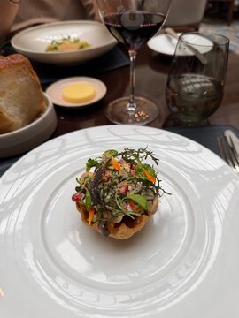 Burrata tartlet with almond, pomegranate and tomatoes served on a white plate