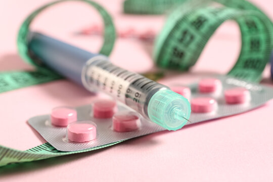 Weight loss medication and diabetes management, insulin pen with pink pills and measuring tape for obesity treatment and metabolic health monitoring