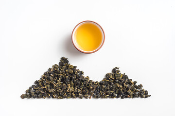 Obraz premium Top view creative flat lay of oolong tea leaves arranged in mountain shape with teacup as sun on white background with copy space