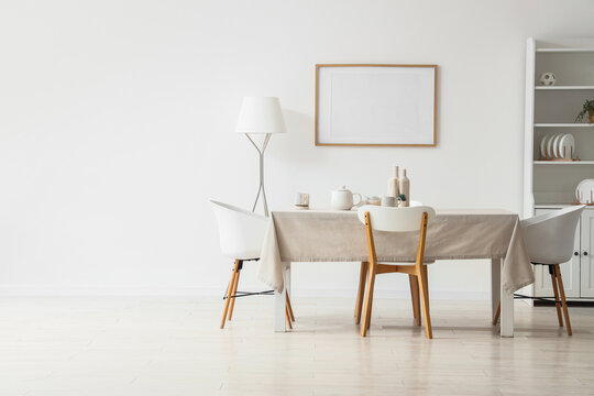Table with chairs, floor lamp and blank poster in interior of dining room