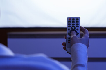 Obraz premium Entertainment and leisure, person holding a television remote control at home while watching movies or streaming media in a dark living room environment