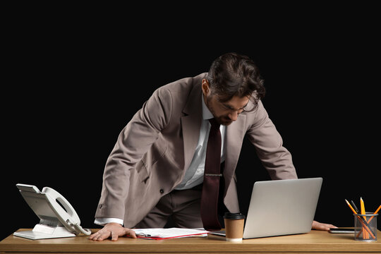 Angry businessman at desk on black background