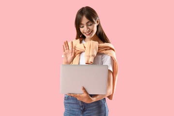 Young woman with laptop video chatting and waving hand on pink background. Hello concept © Pixel-Shot