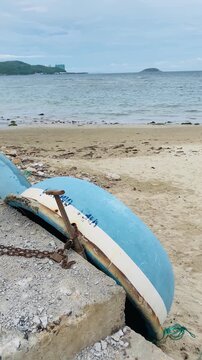 Vertical view of a traditional Vietnamese round coracle boat locked on a sandy beach with the sea and distant hills in Nha Trang, Vietnam.