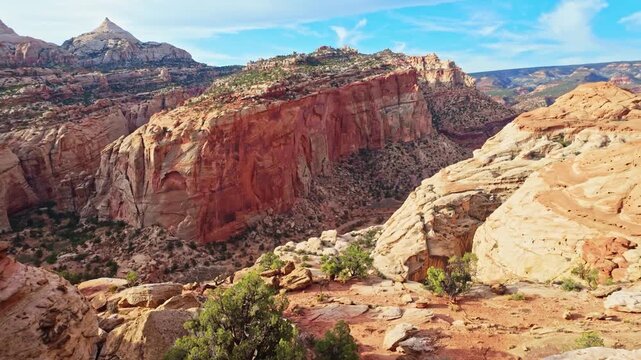 Early morning sunlight illuminates the massive natural sandstone span of Cassidy Arch high above the rugged desert canyon in Utah